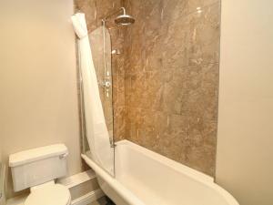a bathroom with a shower and a toilet and a tub at School House in Ivybridge +12 photos