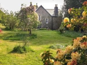 an old stone house with flowers in front of it at School House in Ivybridge