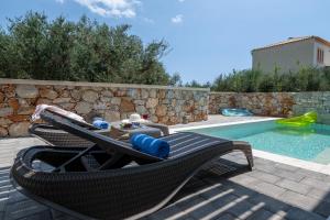 a swimming pool with a chair next to a swimming pool at Pasithea Villas in Neokhórion
