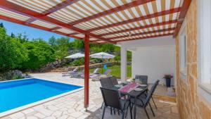een patio met een tafel en stoelen naast een zwembad bij Villa Primabella -Makarska by Villas Guide in Poljica