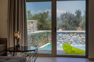 a living room with a view of a pool through a sliding glass door at Pasithea Villas in Neokhórion