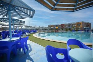 een zwembad met blauwe tafels en stoelen naast een gebouw bij LUSINDA HOTEL MANAGEMENT BY ZAD in Suez