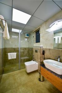 een badkamer met een wastafel, een toilet en een douche bij Hotel Dain Castle, Varkala in Varkala