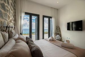 a bedroom with a large bed with a view of the ocean at KYAN Syros in Liaropá