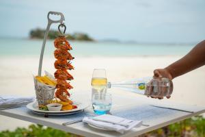 een persoon die een glas wijn en een bord eten schenkt bij Paradise Sun Hotel Seychelles in Baie Sainte Anne