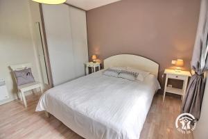 a bedroom with a white bed and two tables at Brin de bonheur in Évran