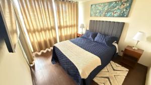 een slaapkamer met een bed met een blauw dekbed en een raam bij Viña del Mar - Parque Marina in Viña del Mar +8 foto's