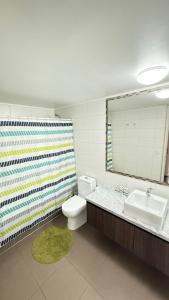 een badkamer met een wastafel, een toilet en een spiegel bij Viña del Mar - Parque Marina in Viña del Mar