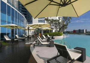 a pool with chairs and umbrellas next to a building at UHF HOTELS and RESORTS PINETREE in Iskandar Puteri