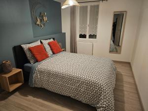 a bedroom with a bed with orange pillows at Gîte de la Tour d'horloge in Carvin