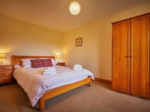 a bedroom with a bed and a wooden cabinet at Hazel Lodge in Blairgowrie