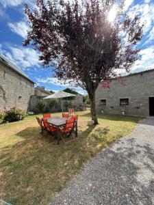 a table and chairs under an umbrella under a tree at La Flore in Baraqueville