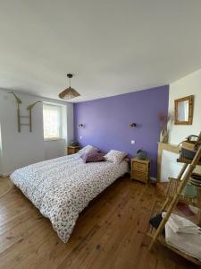 a bedroom with a bed and a purple wall at La Flore in Baraqueville