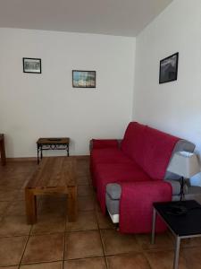 a living room with a red couch and a table at Villa T3 avec piscine in Sollacaro