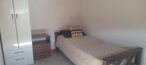 een kleine slaapkamer met een bed en een dressoir bij cabañas sunrise in Merlo