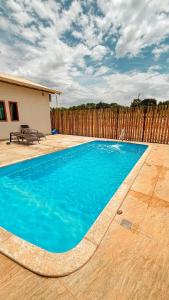 a blue swimming pool in front of a wooden fence at Chalé M in Serra do Cipo