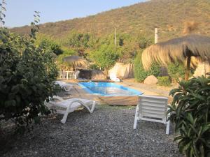 a resort with a pool and chairs and a hut at Cabañas Ciprés in Guayacán
