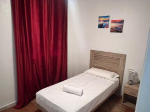 una piccola camera da letto con un letto con una tenda rossa di Apartalux Isla Cristina a Isla Cristina Altre 38 foto