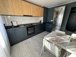 a kitchen with blue cabinets and a white table at V apartament - ultra central Otopeni in Otopeni