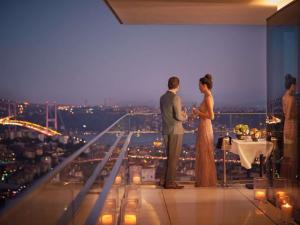 una sposa e uno sposo in piedi sul balcone di un edificio di Raffles Istanbul a Istanbul
