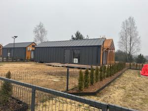 a small black building with trees in a yard at Zakątek Ldzań in Ldzań