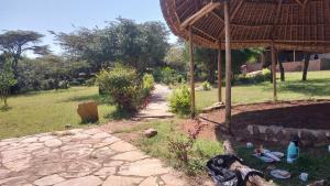 a garden with a straw roof and a path at Mara Sunset Acacia Camp in Sekenani