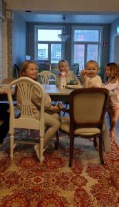 een groep kinderen die aan een tafel zitten met baby's bij Hostel Cafe Huvila in Oulu