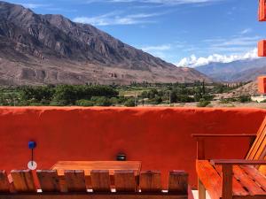 a red wall with a table and a view of mountains at Casa privada en Maimara in Maimará