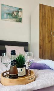 a tray with a bottle of wine and two glasses on a bed at Sabina apartmani in Tuzla