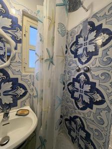 a bathroom with a sink and a blue and white shower curtain at Palazzo Rubina - Dimora mediterranea & SPA in Torre del Greco +30 photos