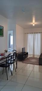 a living room with a table and chairs and a television at Apartamento em Imbituba in Imbituba