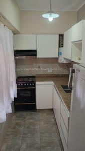 a kitchen with white cabinets and a black stove at Yanel in Mar del Tuyú +2 photos