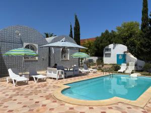 a pool with chairs and umbrellas next to a building at Casa Madame Aïcha in Sousse