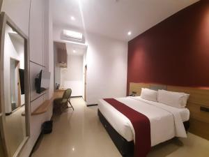 una camera d'albergo con un letto e una televisione di Parkside Meuligoe Hotel a Meulaboh