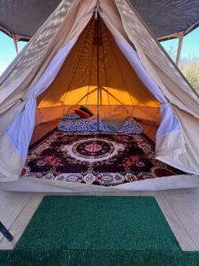 a bed in a tent with a rug in it at Retiro Bajoestrellas in San Pedro de Atacama