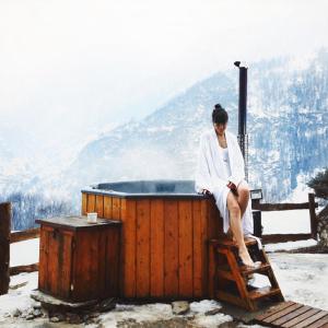 uma mulher sentada num banco ao lado de uma banheira de hidromassagem em Brieis Relais Alpino em Marmora