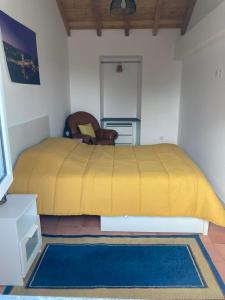 a bedroom with a bed with a yellow bedspread and a chair at Casa Isqueiro in Cela