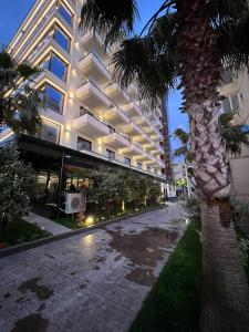 una strada vuota di fronte a un edificio con una palma di Sunrise Apartment Qerret a Kavajë