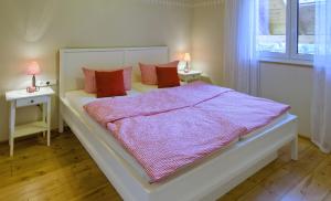 een slaapkamer met een groot wit bed met rode kussens bij Ferienhof Spöcker in Gerbertshaus
