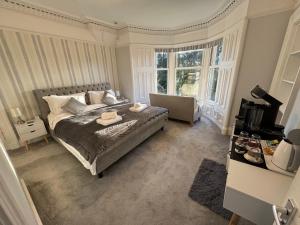 a bedroom with a bed and a couch and windows at Crannaig House in Aberfoyle