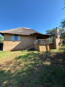 a brick house with a deck on a yard at Inyala Game Lodge in Ventersdorp