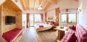 ein großes Zimmer mit einem Bett und einem Fernseher darin in der Unterkunft Hotel Kasimir in Riezlern