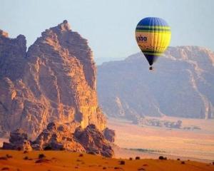 a hot air balloon flying over a desert with mountains at Wadi Rum in Al Jafr +1 photo