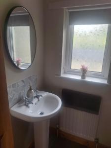 a bathroom with a sink and a mirror and a window at Redbrae cottage in Carnlough
