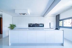 a white kitchen with white cabinets and a sink at Appartement luxe hivernage in Marrakesh +1 photo