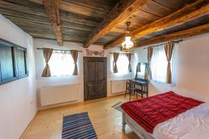 a bedroom with a bed and a table and windows at Pensiune Old Barn House in Vàrhegy
