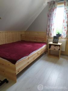 a bedroom with a wooden bed and a window at Dom nad jeziorem Serwy in Serwy