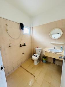 een badkamer met een toilet, een wastafel en een spiegel bij Winlee house in Ban Phlu Yai
