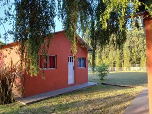 ein rotes Haus mit weißer Tür in einem Hof in der Unterkunft complejo parenzo in Camet