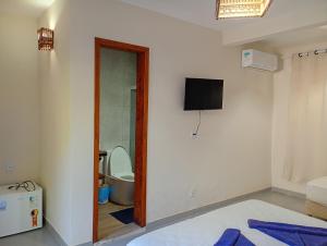 een badkamer met een toilet en een televisie aan de muur bij Pousada Caminho da Concha in Itacaré